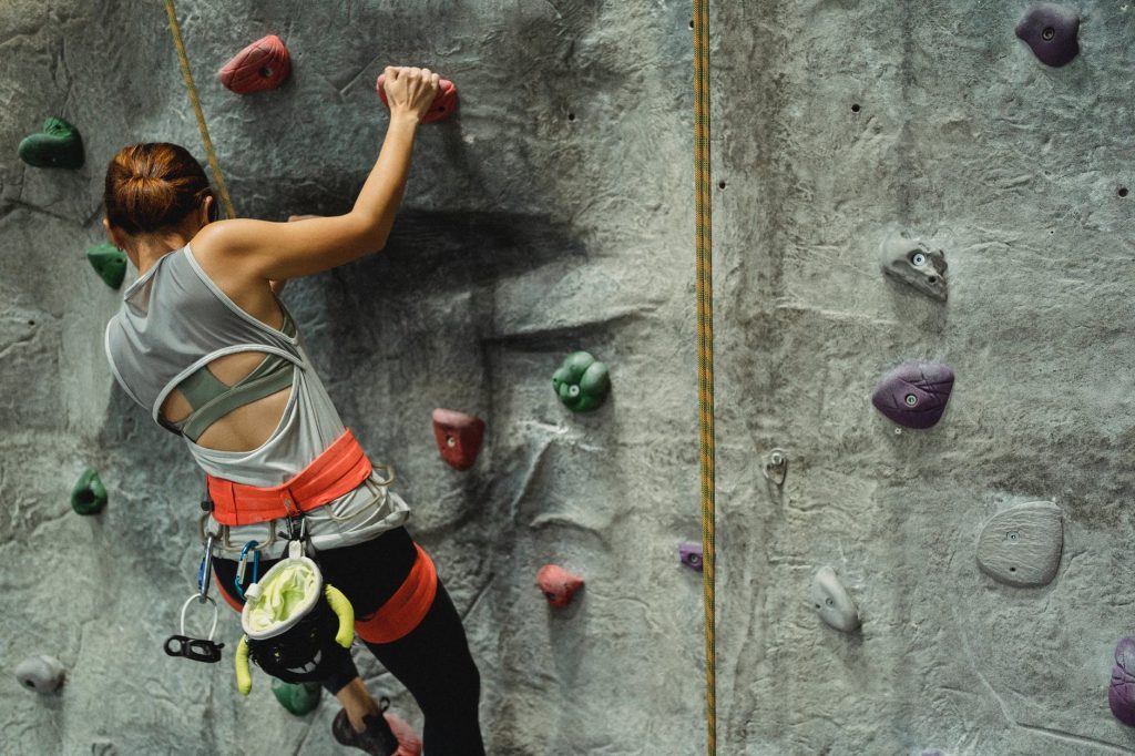 unrecognizable climber ascending artificial rock with holds